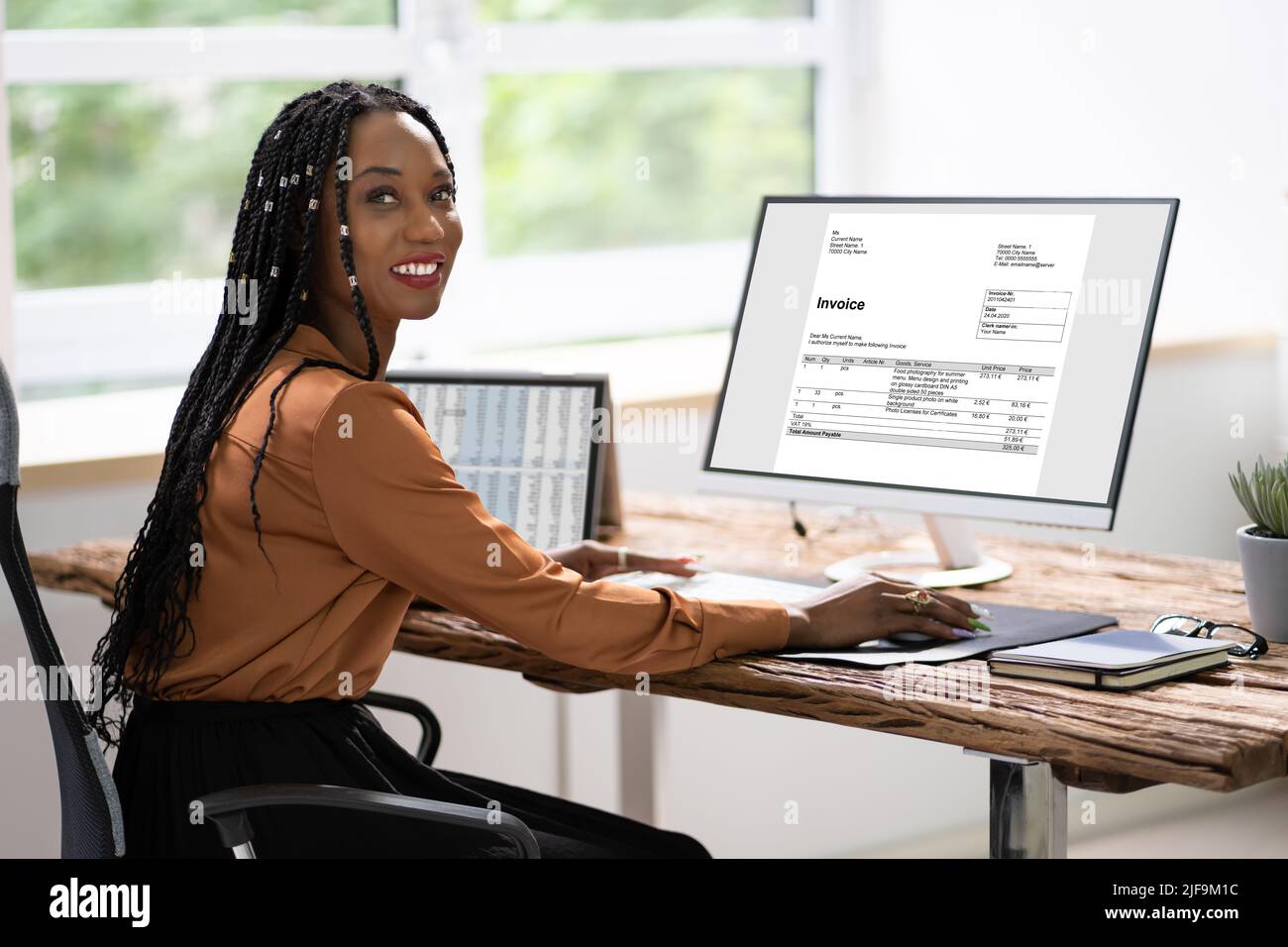 African American Lady Using Computer For Online Invoice Calculation Stock Photo