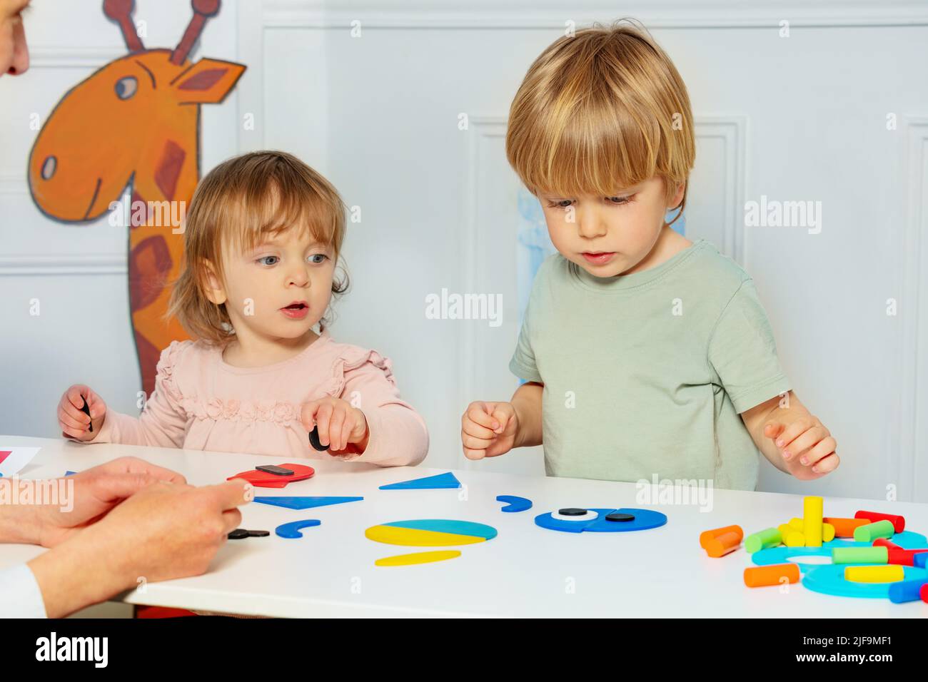Little kids boy and a girl put together shapes on the table Stock Photo