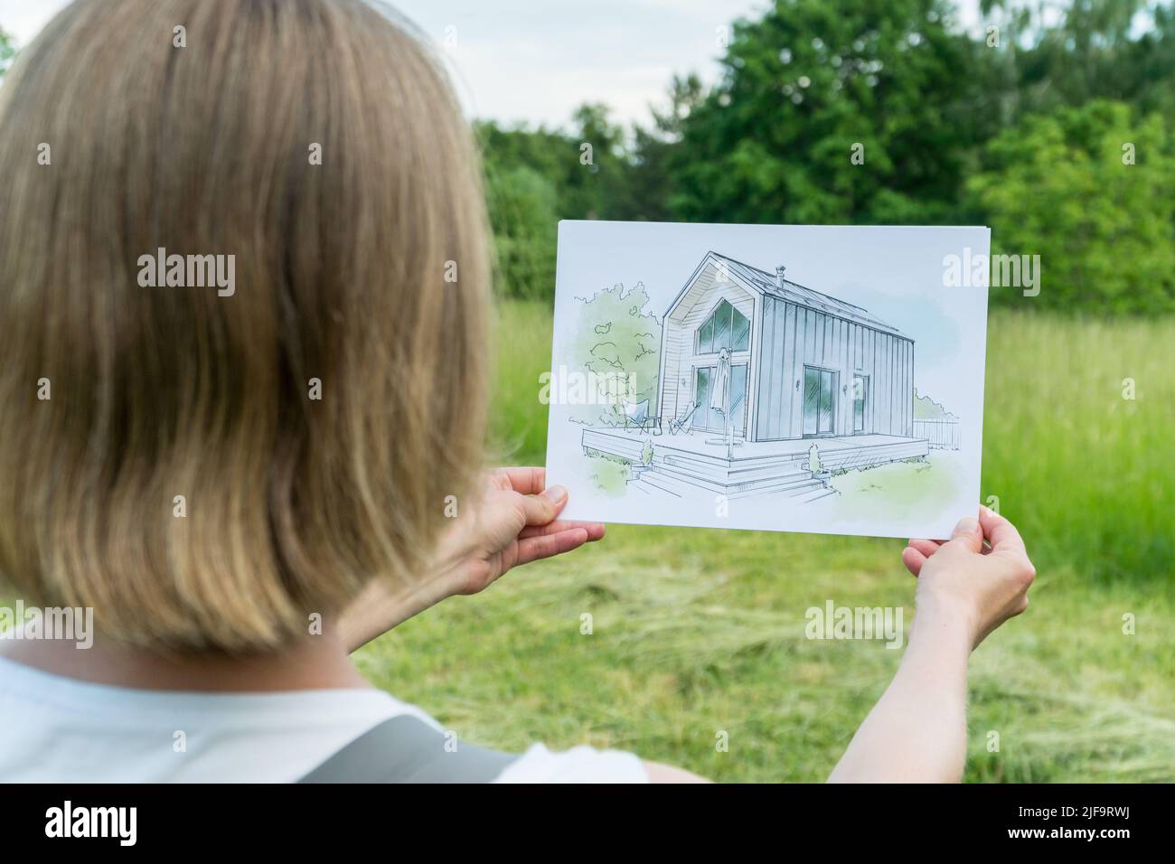 Architect holding barn house  hand drawn sketch in front of a plot of land.  Architectural design concept Stock Photo