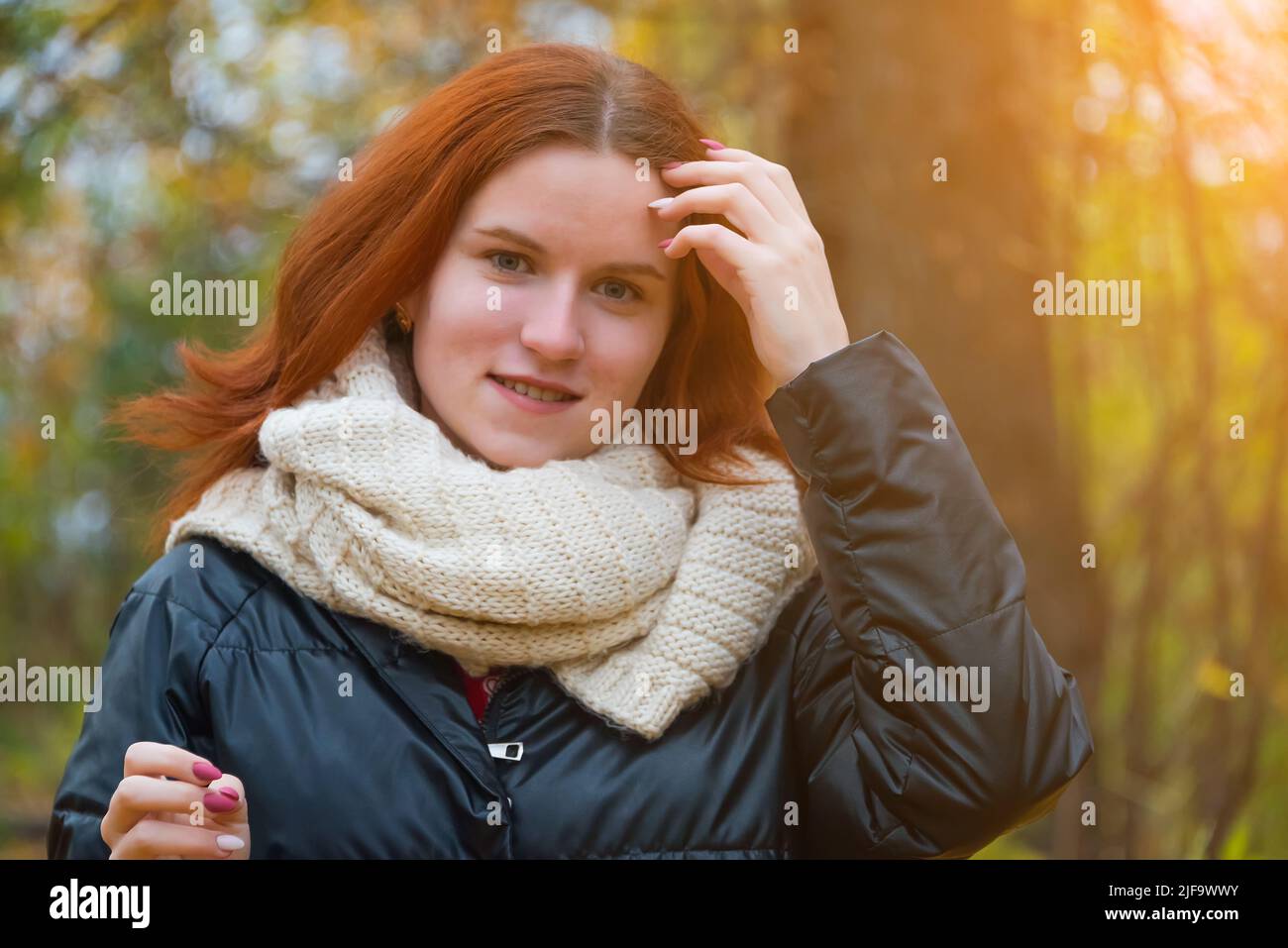 portrait of a red-haired smiling girl in a jacket and scarf ...