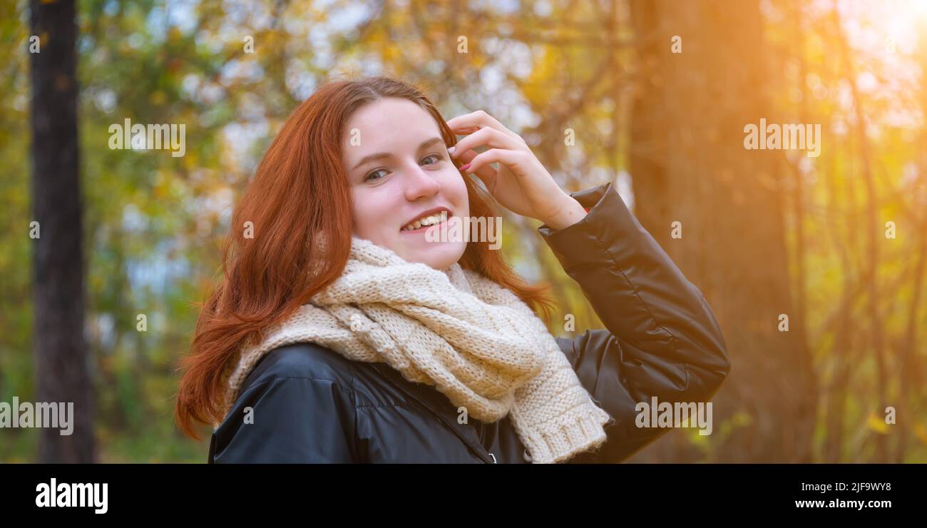 portrait of a red-haired smiling girl in a jacket and scarf ...
