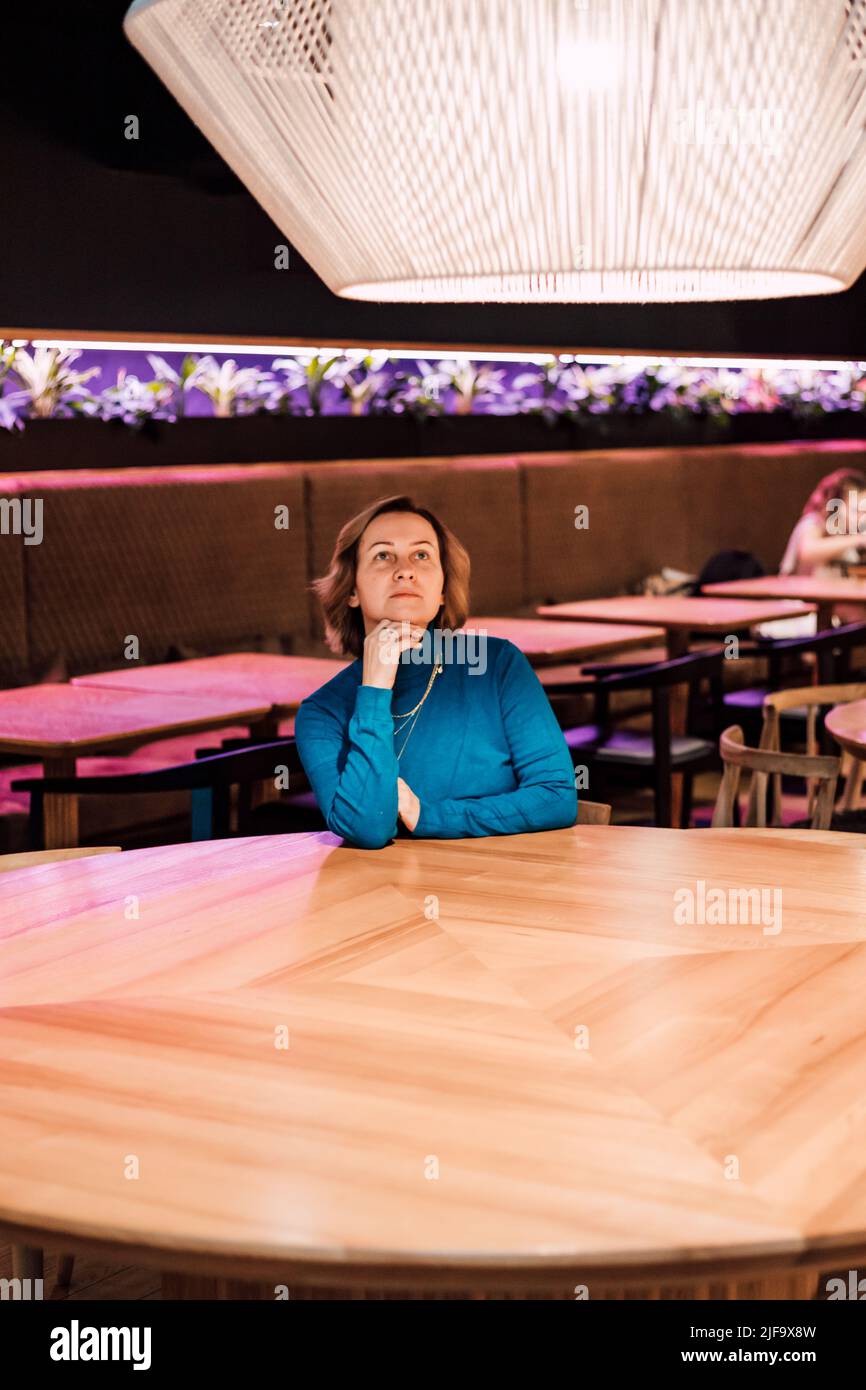 A beautiful woman sits at a table in a restaurant alone Stock Photo