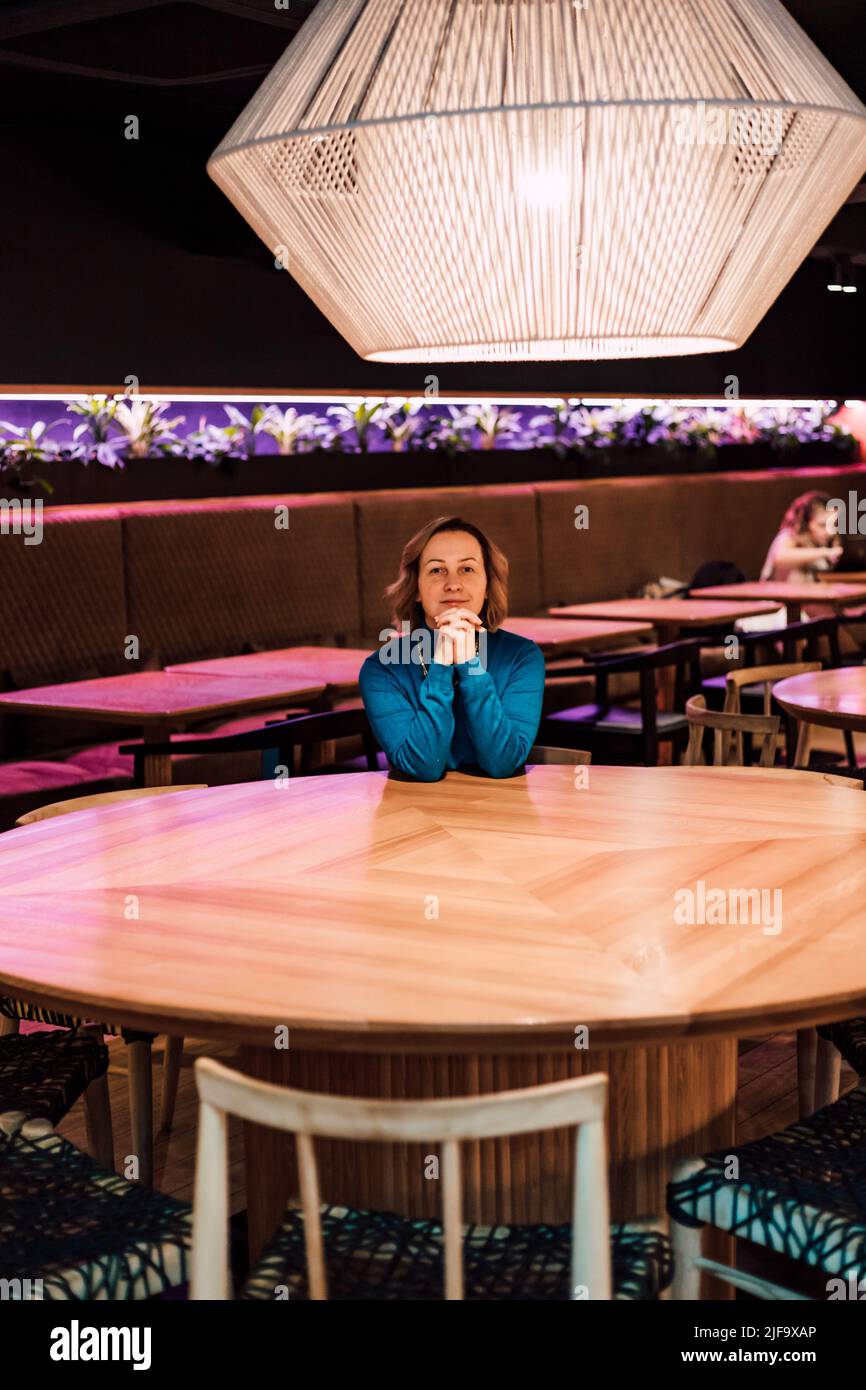 A beautiful woman sits at a table in a restaurant alone Stock Photo