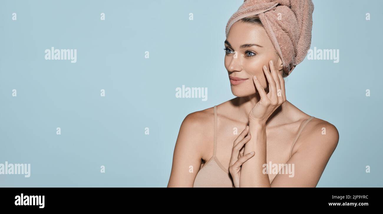 Happy woman with moisturized fresh skin with towel on head after bath procedures on blue background. Body care concept Stock Photo
