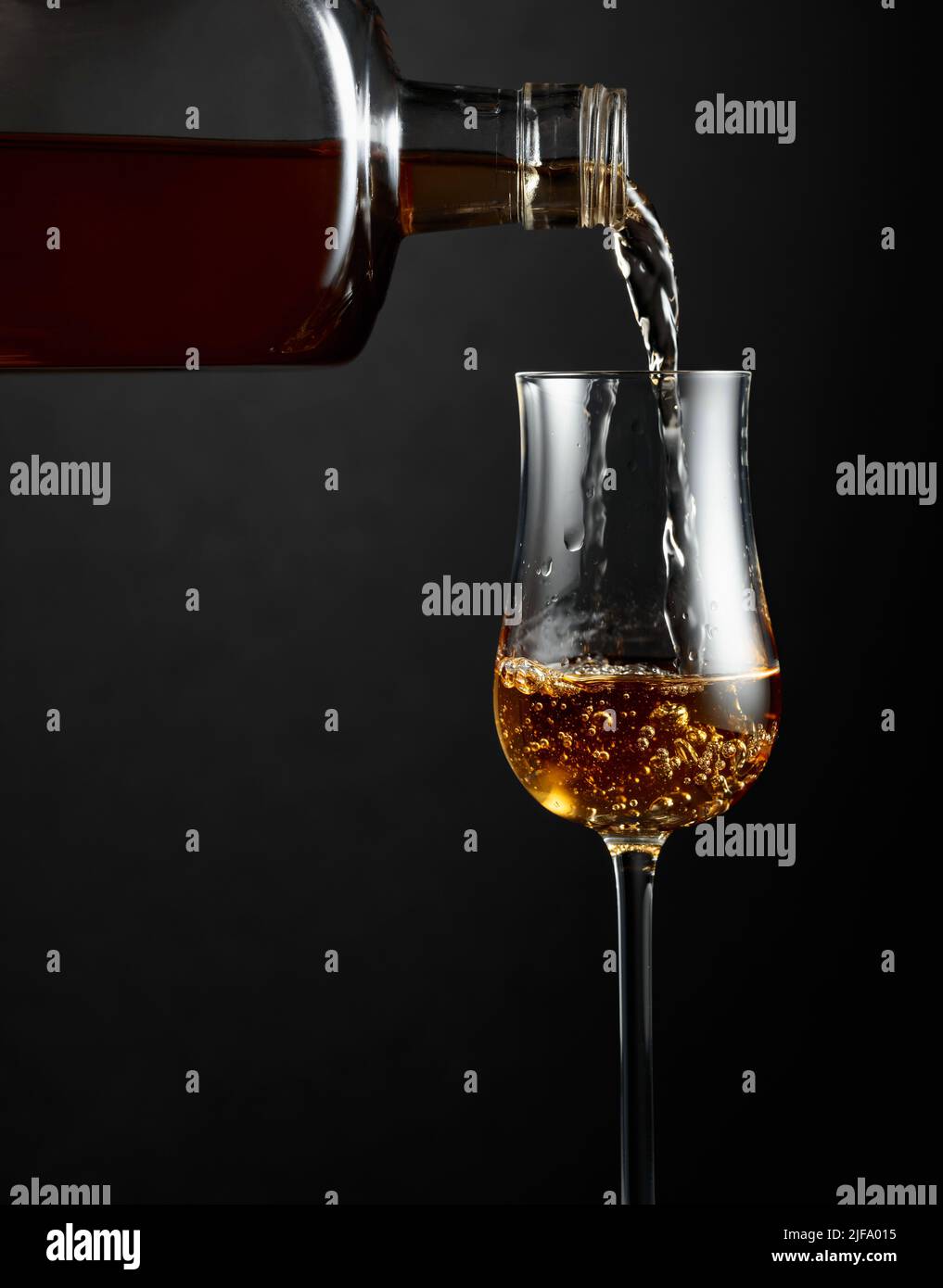 Strong alcohol drink is poured from a bottle into a glass. Copy space