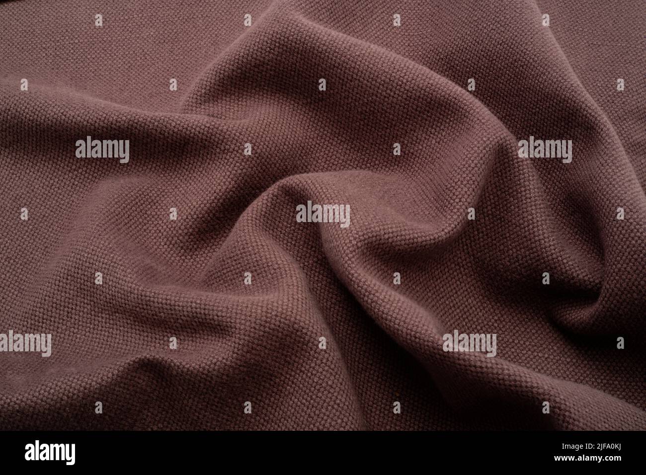 Textured fabric background. A puce or aubergine coloured fabric ruched up to add wavyness. Stock Photo