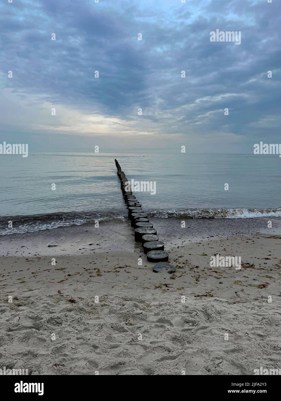 A vertical shot of breakwater built of wooden logs by the ocean Stock ...