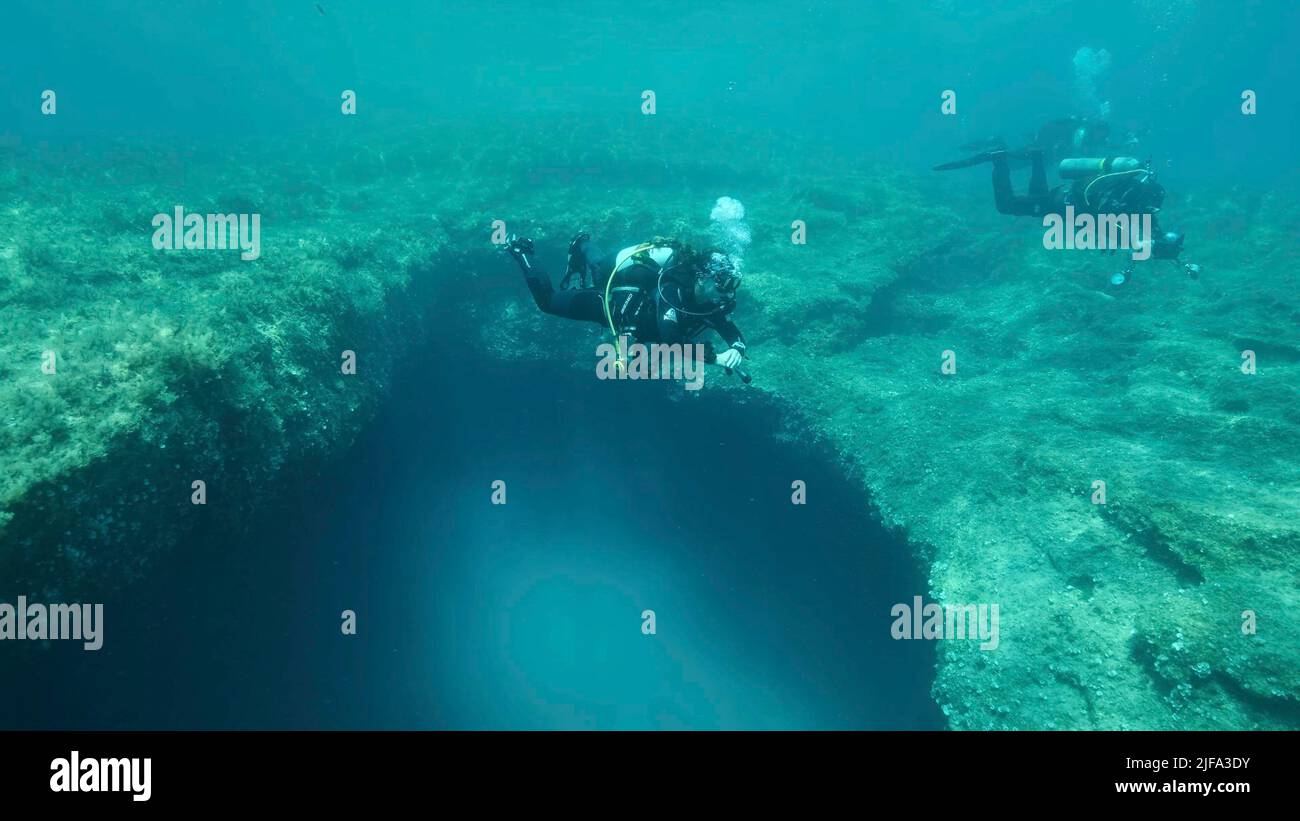 Female scuba diver near the exit from the cave. Cave diving in Mediterranean Sea, Cyprus Stock Photo