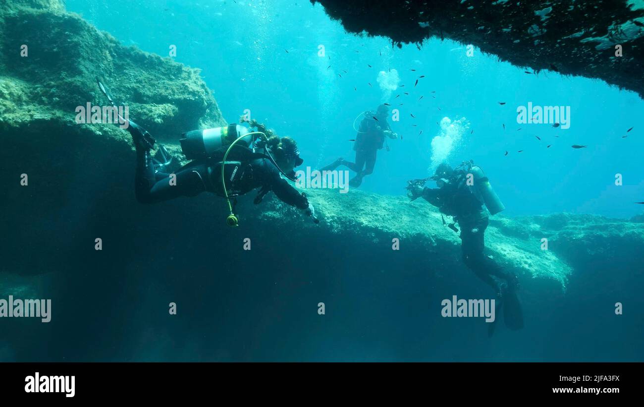 Group of scuba divers swim in the cave. Cave diving in Mediterranean Sea, Cyprus Stock Photo