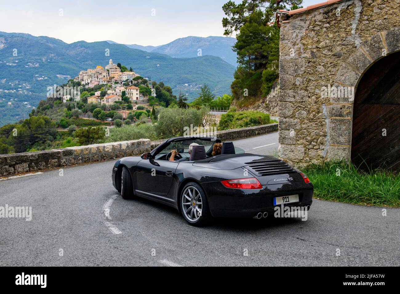 Sports car convertible Porsche 911 in tight curve of historic track section of Rally Monte Carlo 1965, in the background La Roquette-sur-Var Stock Photo