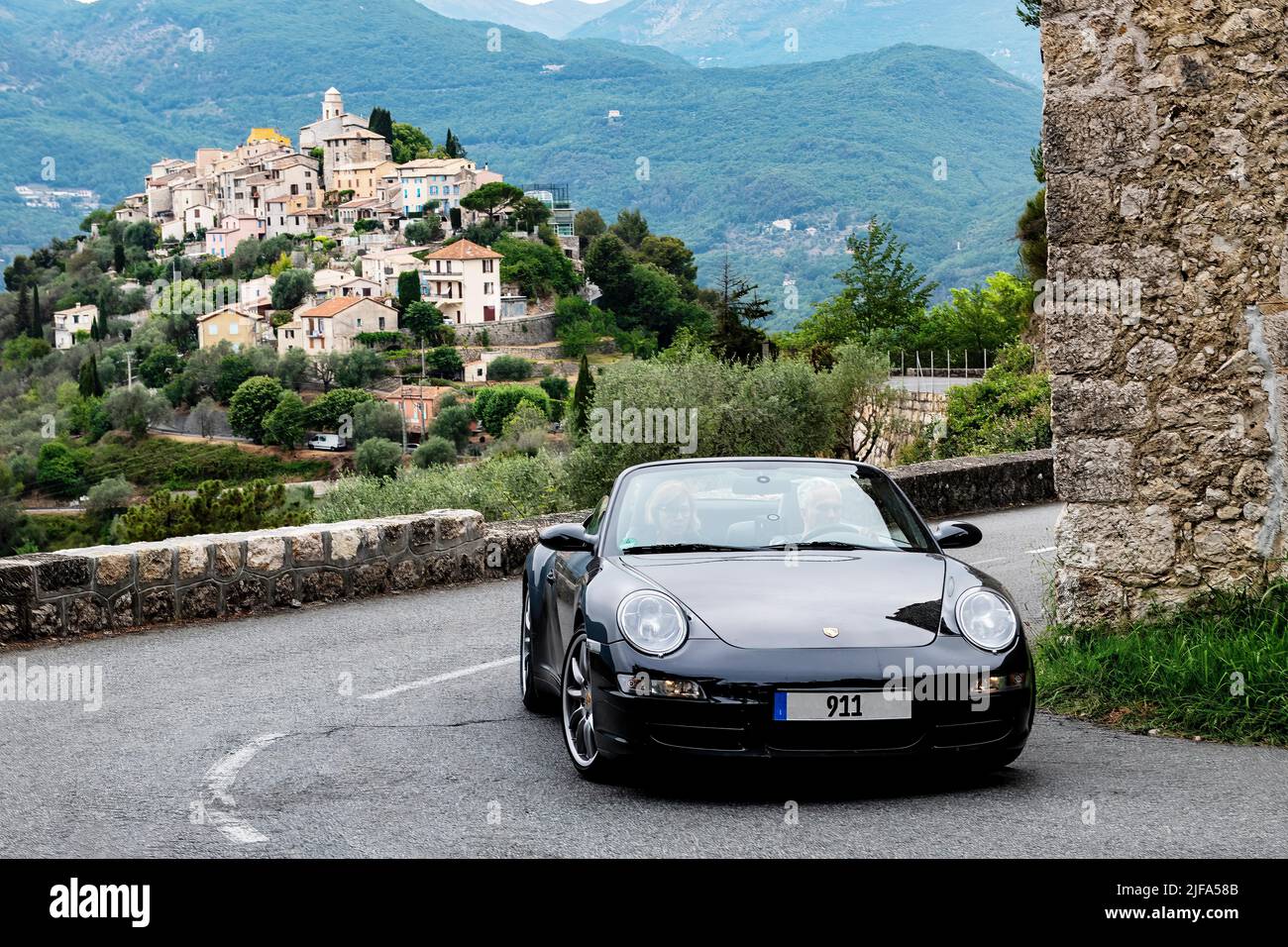 Sports car convertible Porsche 911 in tight curve of historic track section of Rally Monte Carlo 1965, in the background La Roquette-sur-Var Stock Photo