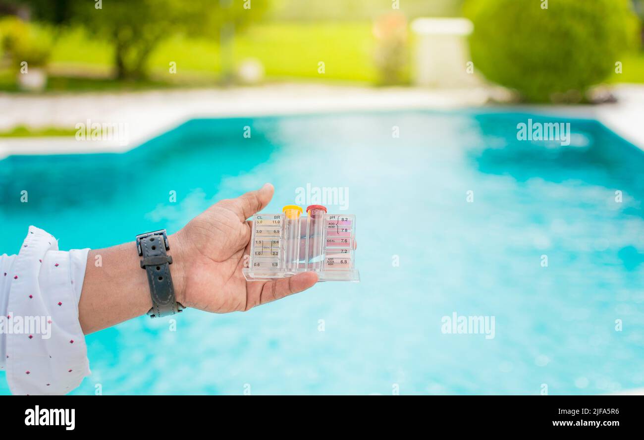 Hand holding Water Test Kit on blurred pool background, Hand holding a