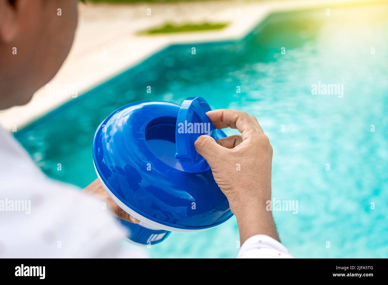 Hand of a pool disinfection worker holding a chlorine dispenser. Hands