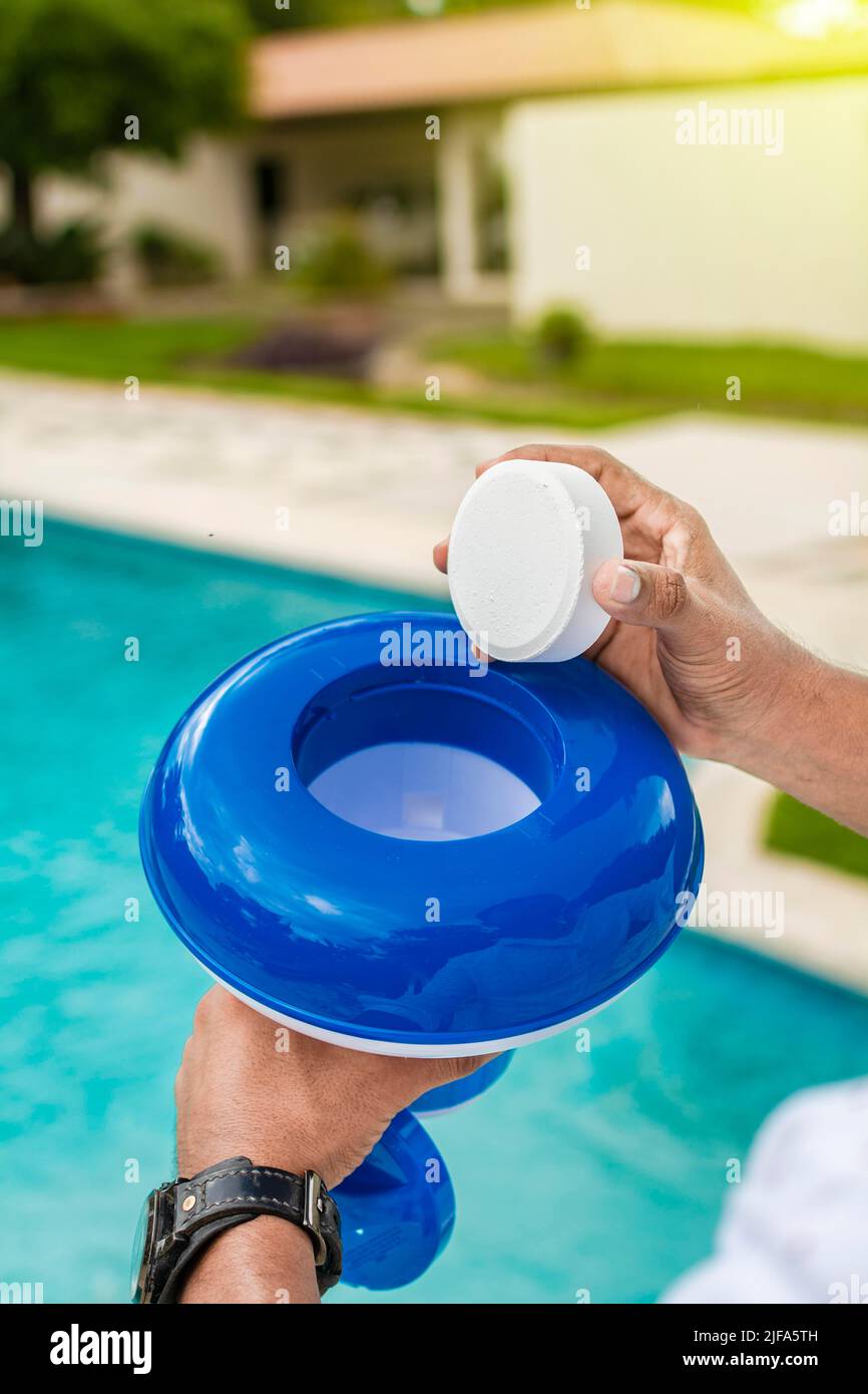 Hand of a pool disinfection worker holding a dispenser with a chlorine