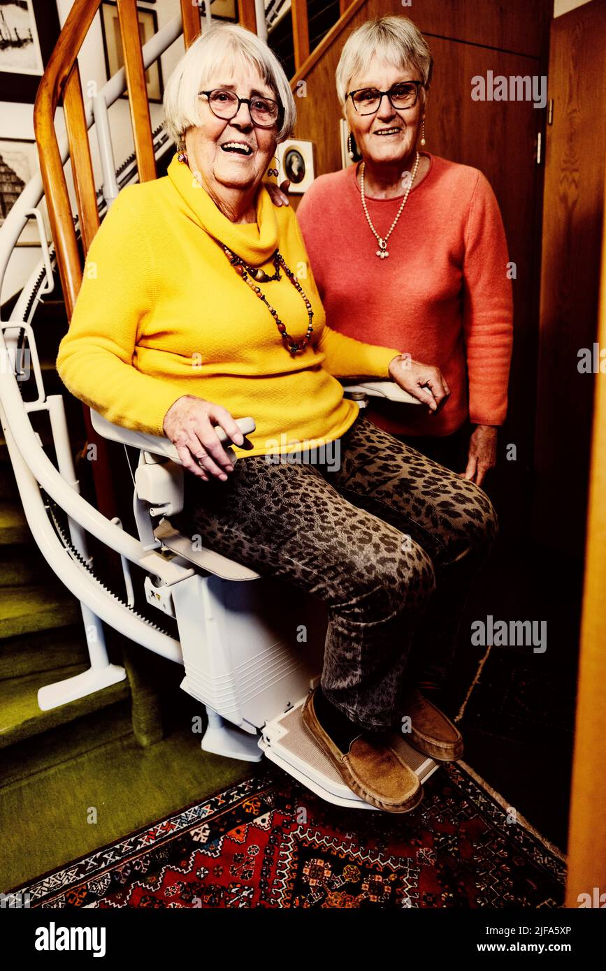 Two senior citizens, sisters, at home with their stair lift, Bocholt, North Rhine-Westphalia, Germany Stock Photo