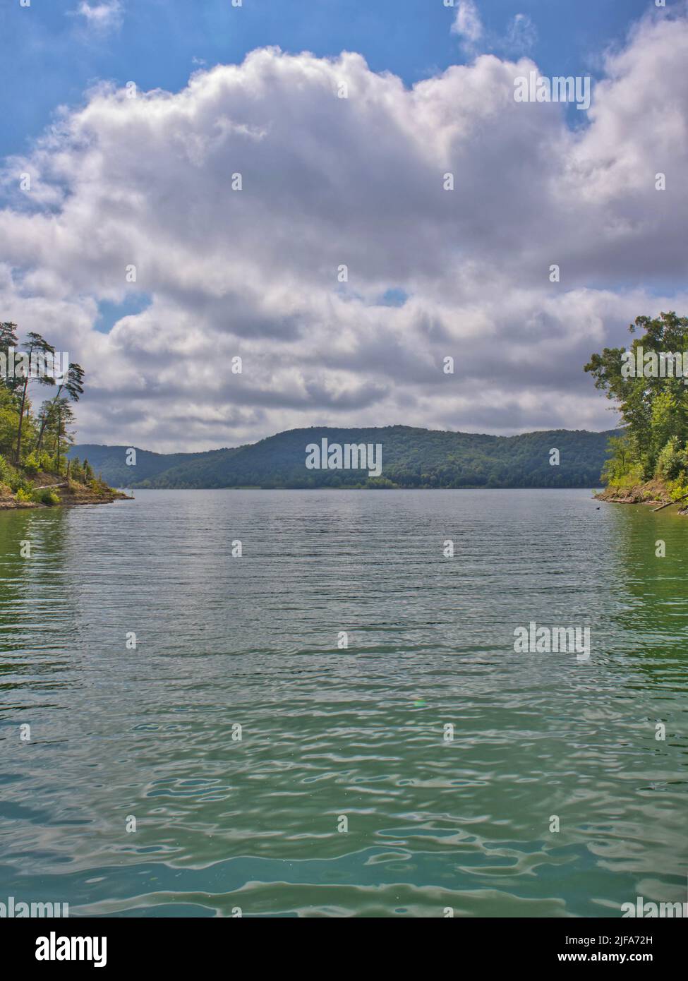A calm lake surrounded by mountains on a cloudy sky Stock Photo - Alamy