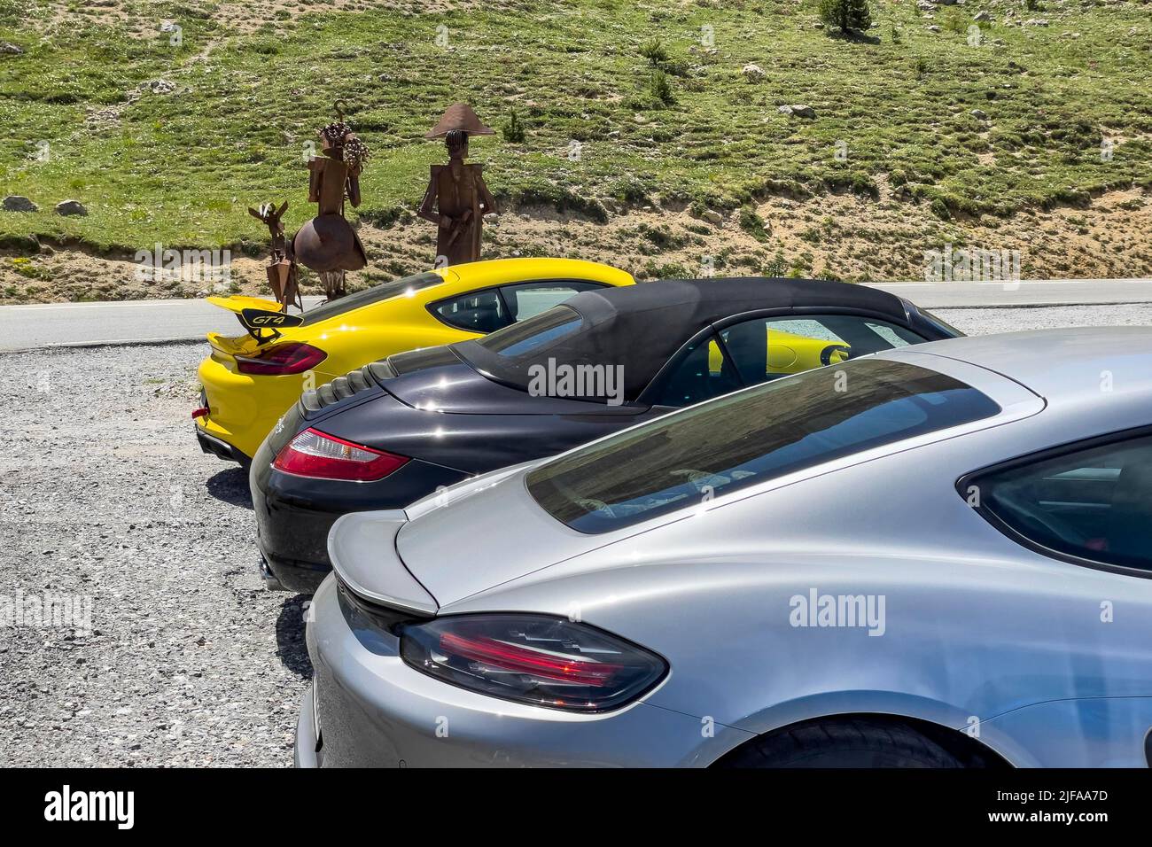 Rear of three sports cars, Porsche Cayman 981 in front, Porsche 911 997 in the middle, Porsche Cayman GT4 in the back, metal sculpture of Emperor Stock Photo