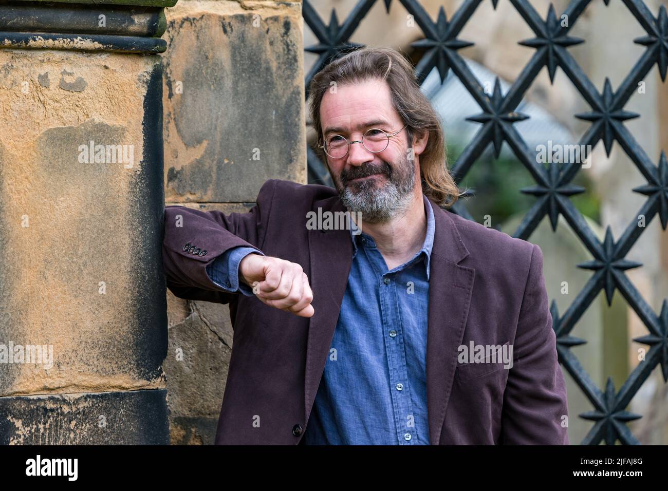 Scottish crime writer author James Oswald in South Leith Parish Church graveyard by an ornate grille in a mausoleum, Edinburgh, Scotland, UK Stock Photo