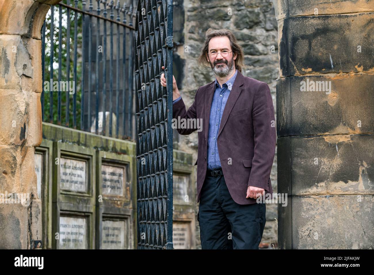 Scottish crime writer author James Oswald in South Leith Parish Church graveyard by an ornate grille in a mausoleum, Edinburgh, Scotland, UK Stock Photo