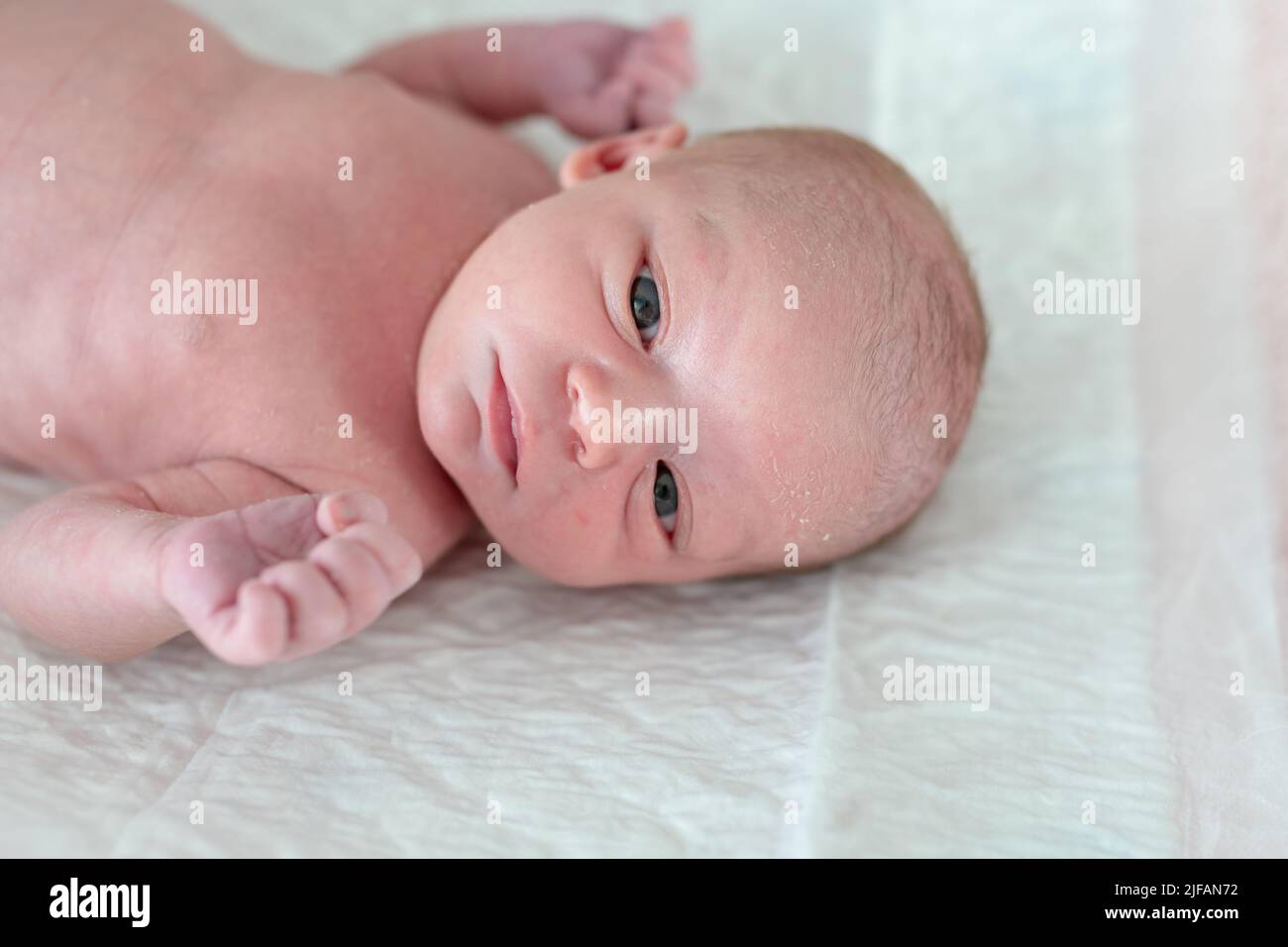 newborn baby with days of life lying in bed ready to be bathed in his