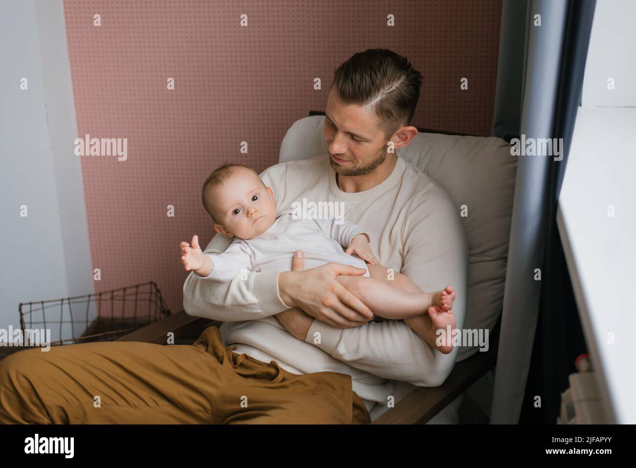 A young Caucasian father holds his sweet sleep baby in his arms