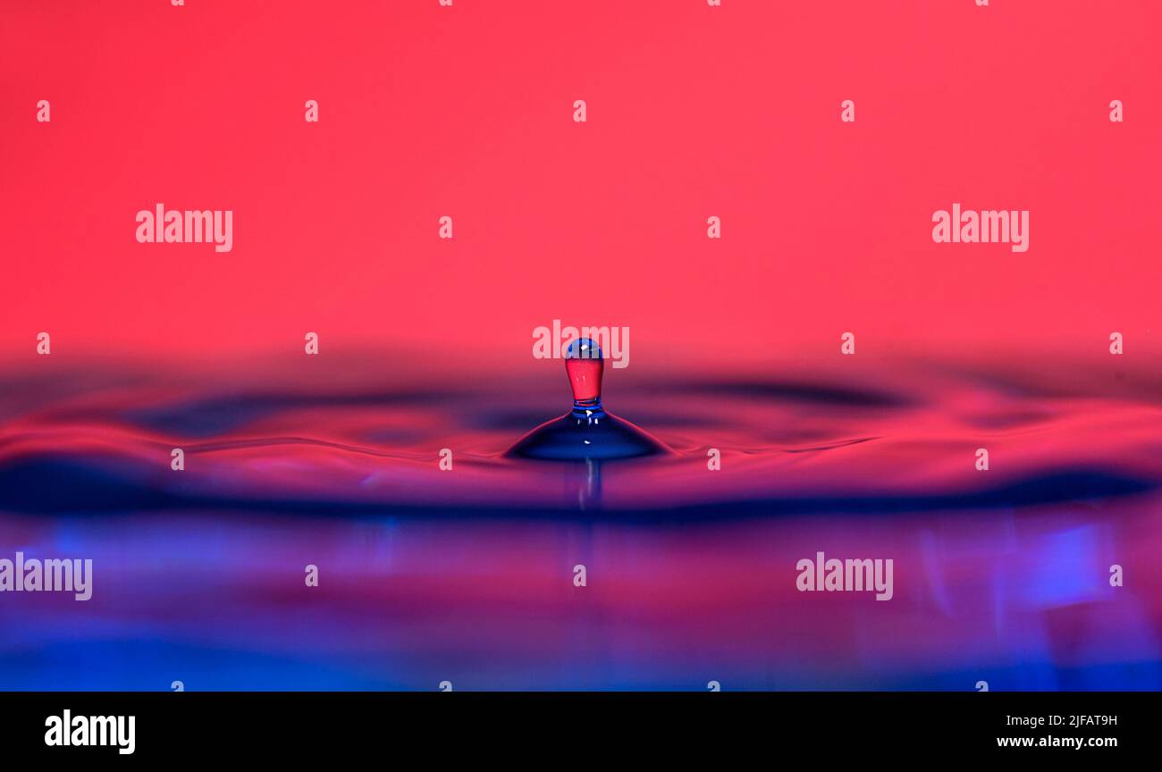 A water droplet falls on a coloured surface Stock Photo Alamy