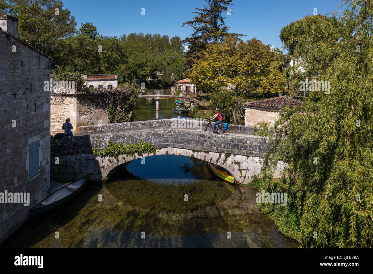 France, Charente, Bassac, cyclist cycling the Flow Veloroute Vélo crossing the bridge over the Guirlande, a small tributary of the Charente river which crosses the foot of the village (aerial view) Stock Photo