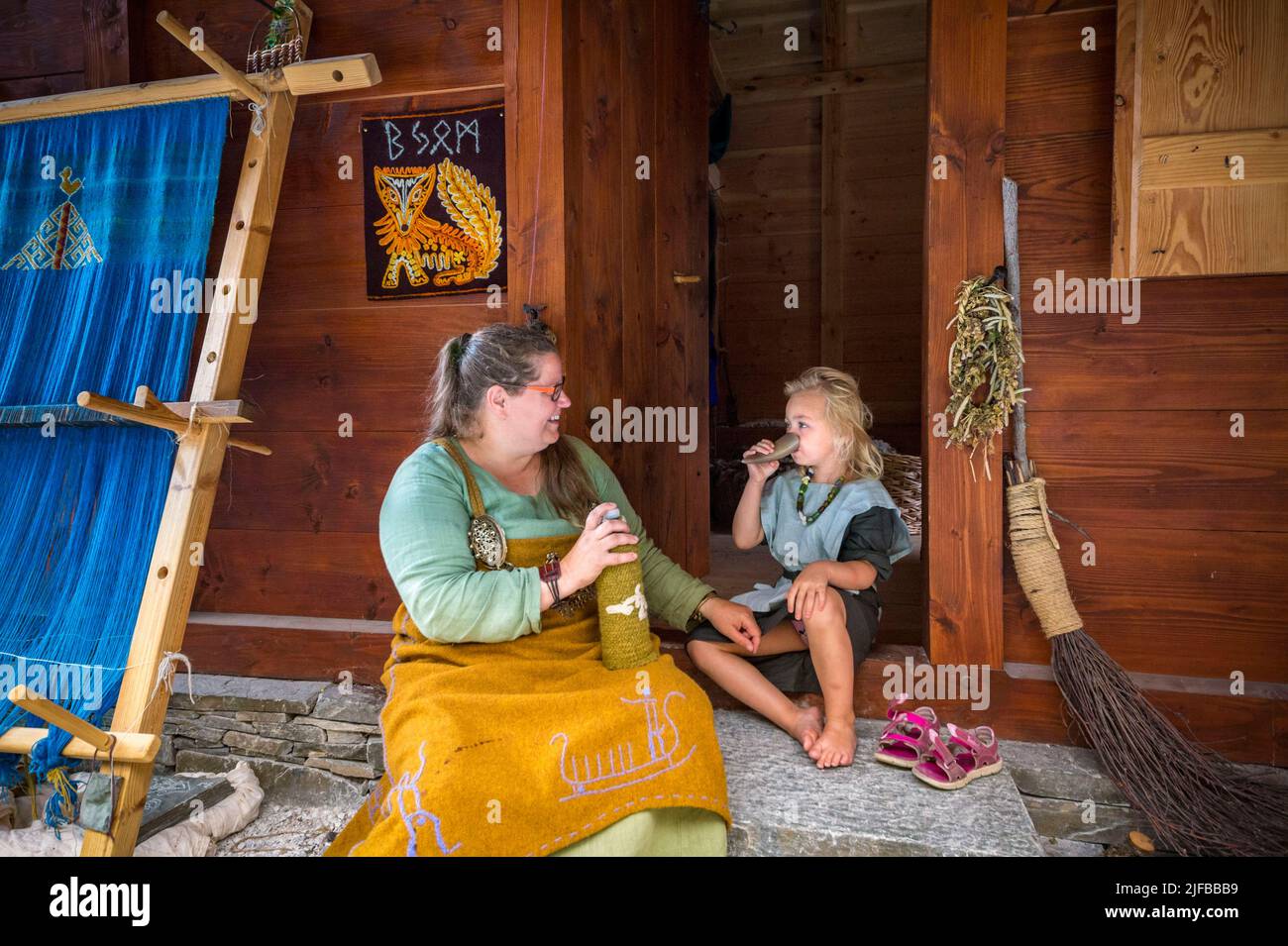Norway, County of Vestland, Naeroyfjord, Aurland, Gudvangen, Viking village, a mother and her child quench their thirst in front of the traditional house which they occupy for a few months, even a few years, living in Viking fashion and passing on their know-how to visitors Stock Photo