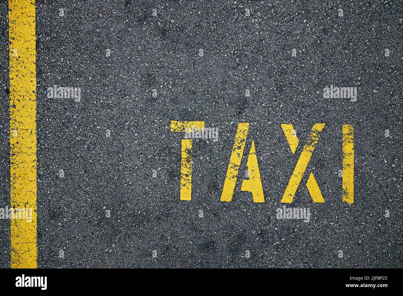 Yellow line and taxi sign on rough asphalt road in city. Stock Photo