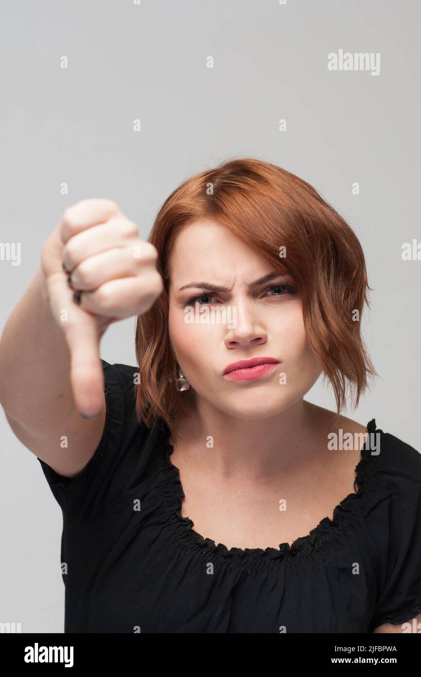 Expressive unhappy young girl thumbs down Stock Photo