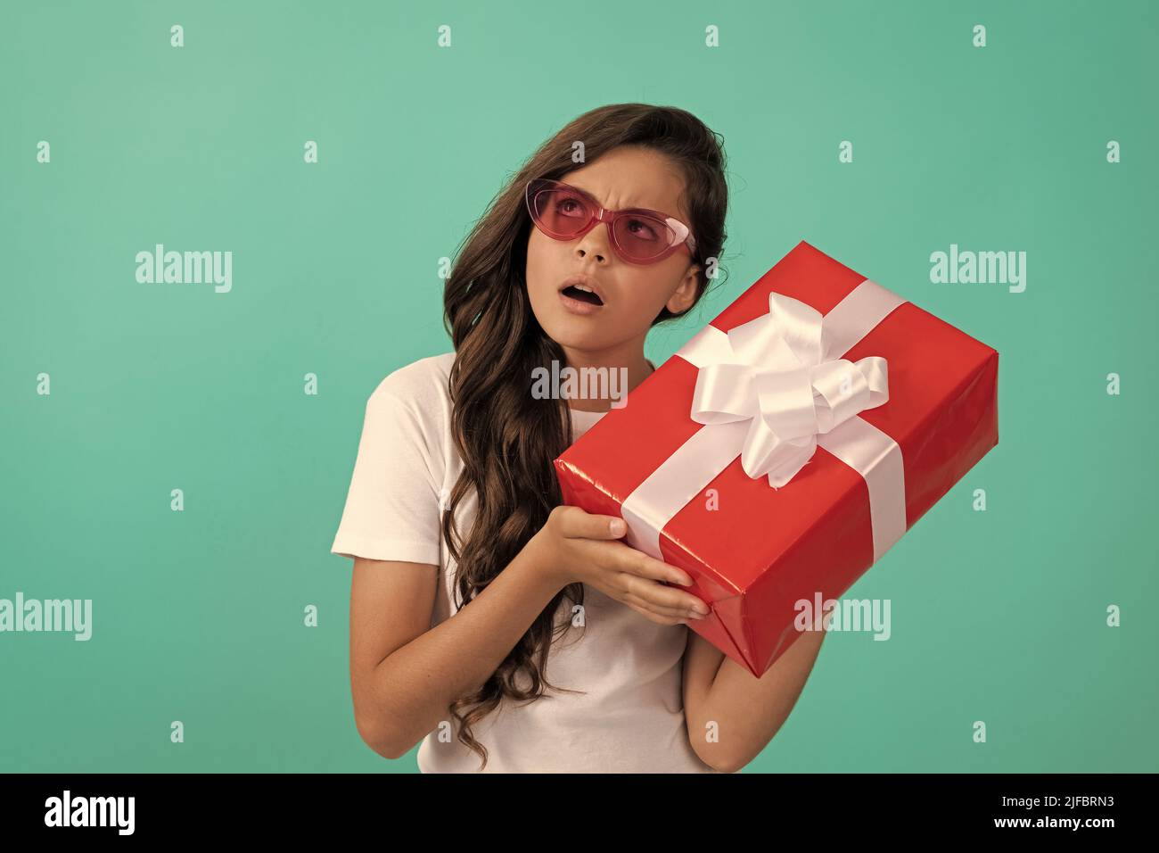 fashionable curious kid in sunglasses hold gift box, curiosity Stock Photo