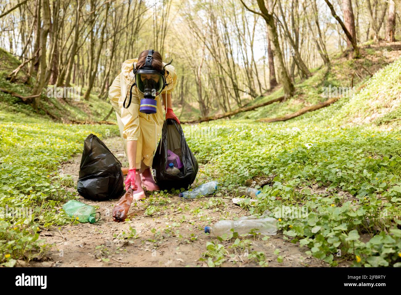 Garbege Protection Mask Woman in gas mask and protective clothes collecting scattered plastic ...