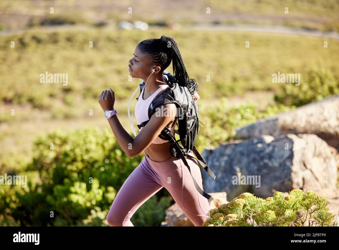 Fit and active African American woman listening to music with earphones ...
