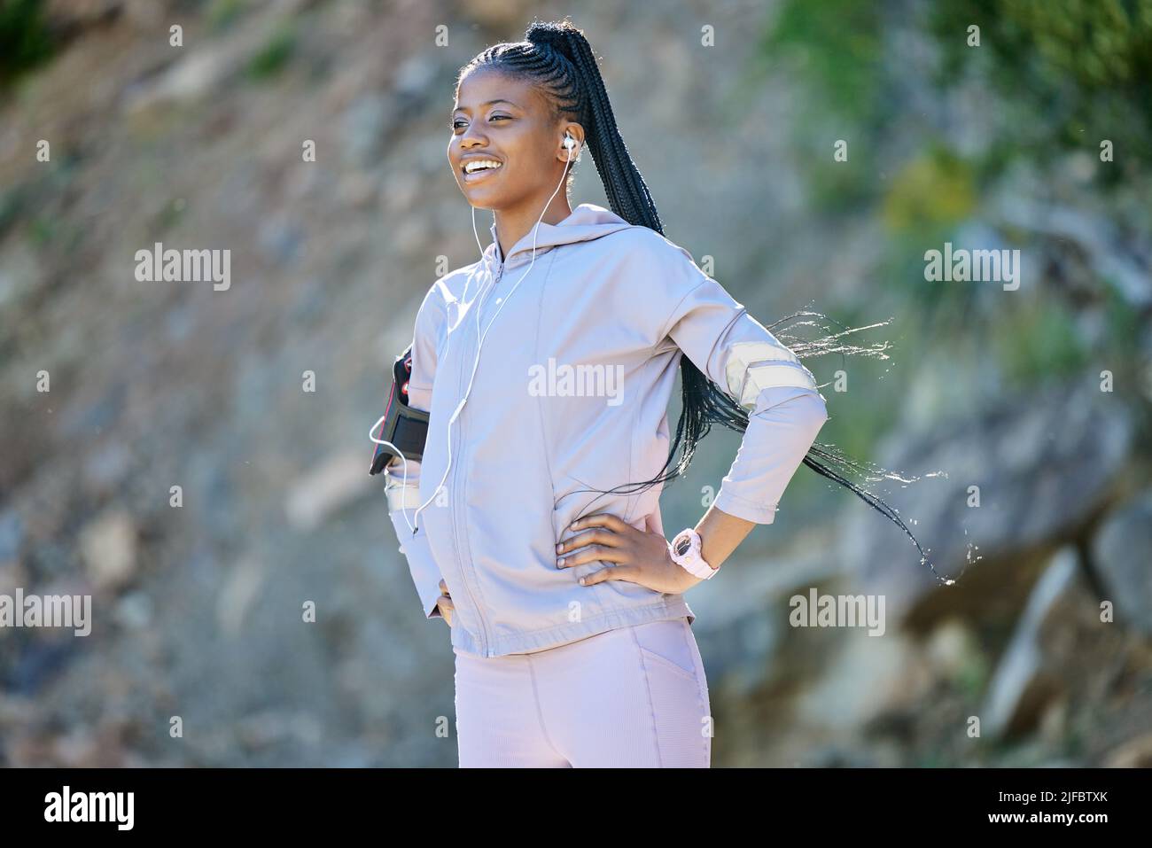 Young happy african american woman hiking on a mountain, taking a break to rest. Black ethnic fit smiling young woman working out in nature. Athletic Stock Photo