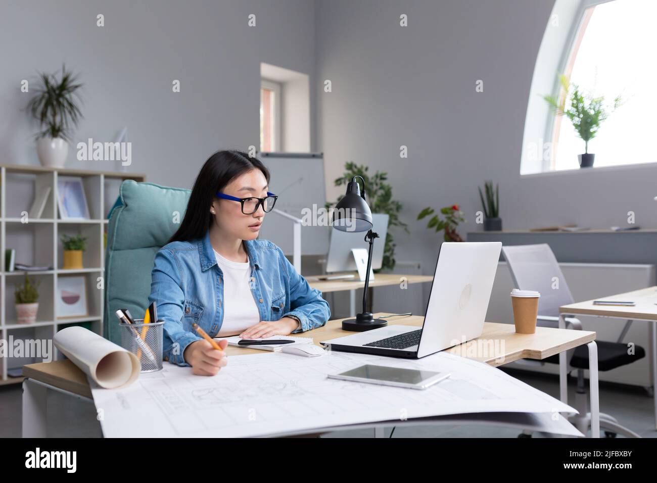 Young beautiful Asian female architect working on a project in an architectural office studio. Stock Photo