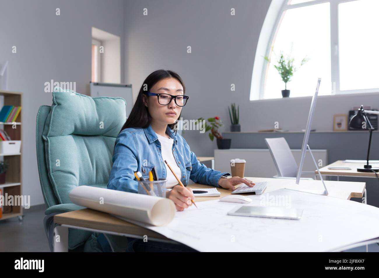 Young beautiful Asian female architect working on a project in an architectural office studio. Stock Photo