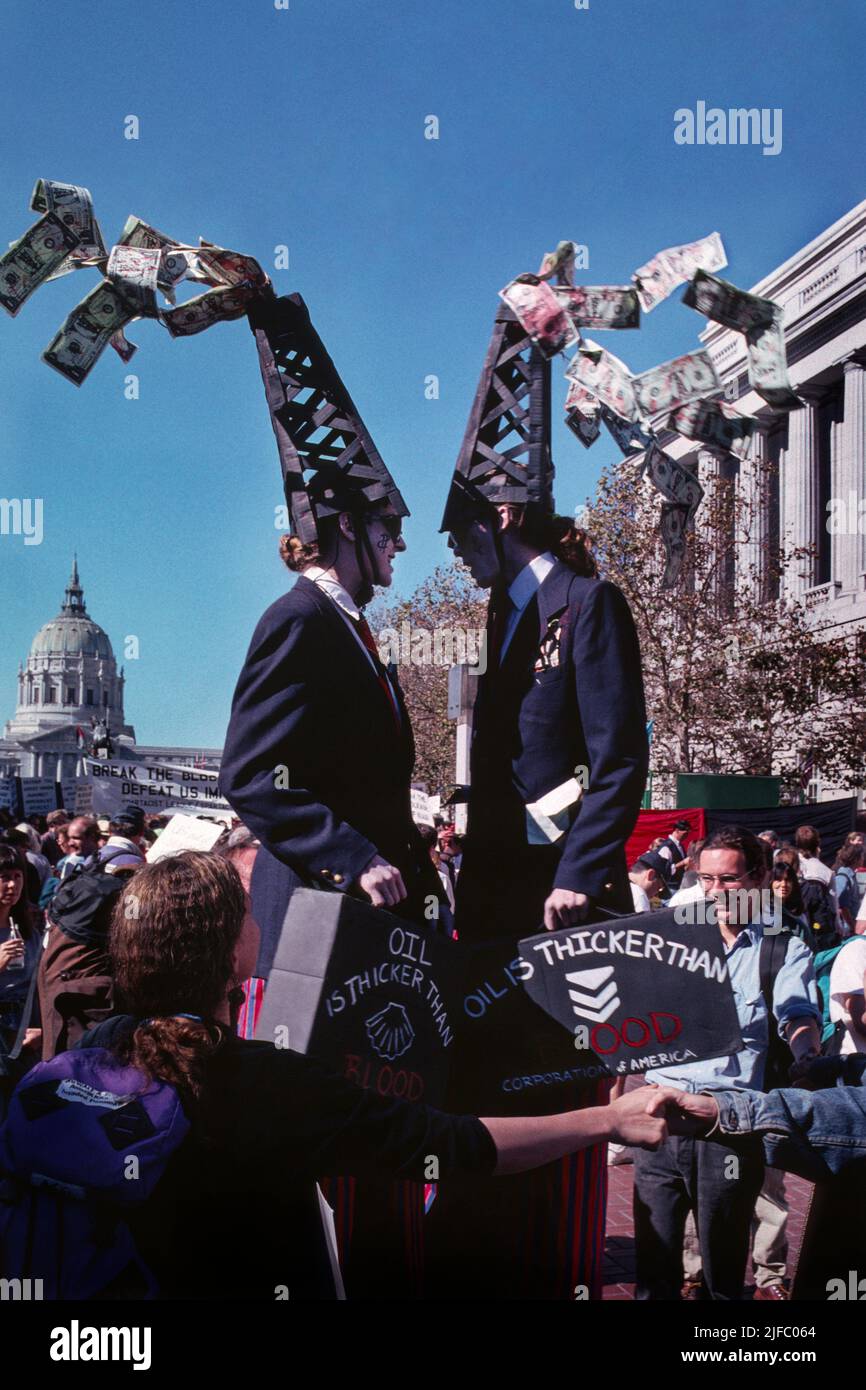 Performance artists on stilts protesting Oil companies and the United States military in the Middle East during the Persian Gulf crisis.  The demonstrators, dressed as “big Oil” executives wore oil derricks spewing blood-stained U.S. dollars, stood outside the U.S. Federal Building on the Civic Center Plaza in Central San Francisco, California in October 1990. Stock Photo