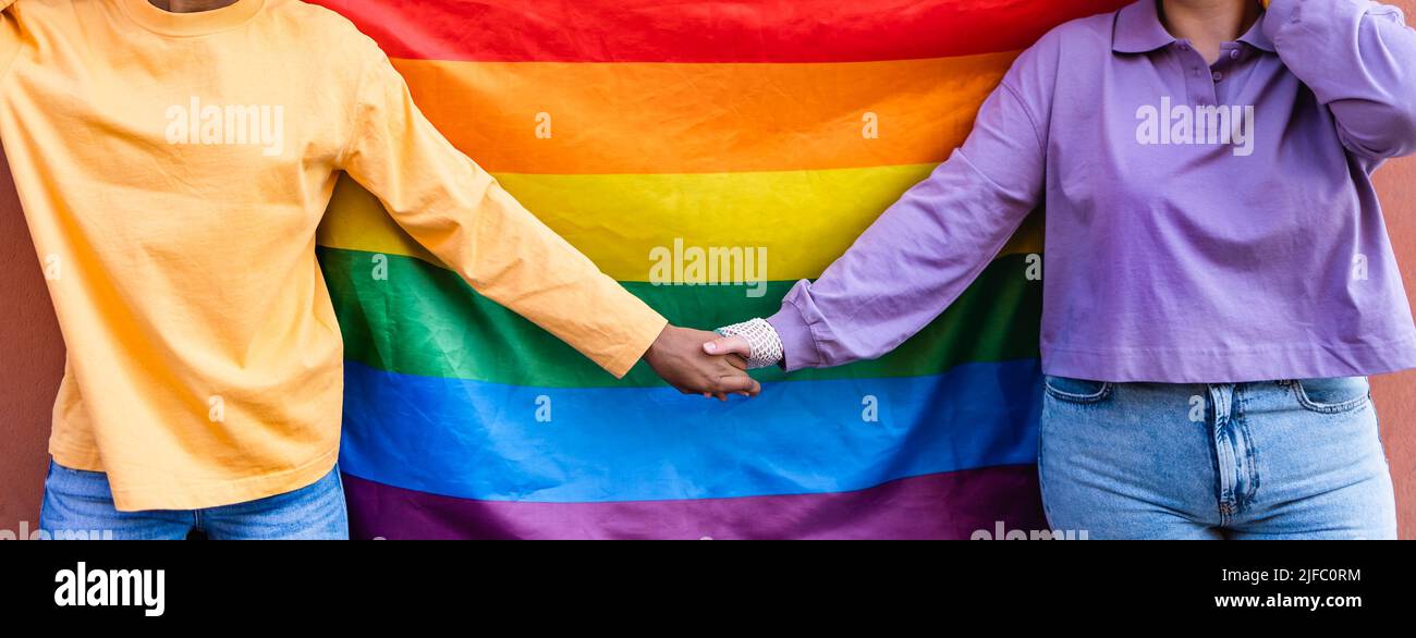 Happy gay couple holding hands while celebrating LGBTQ pride parade Stock Photo