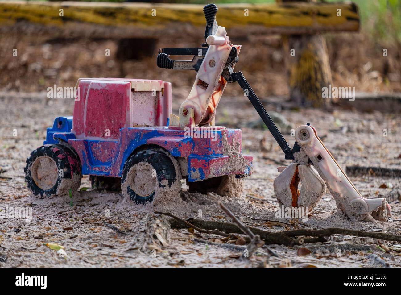 plastic toy car damaged and abandoned in sand. Stock Photo