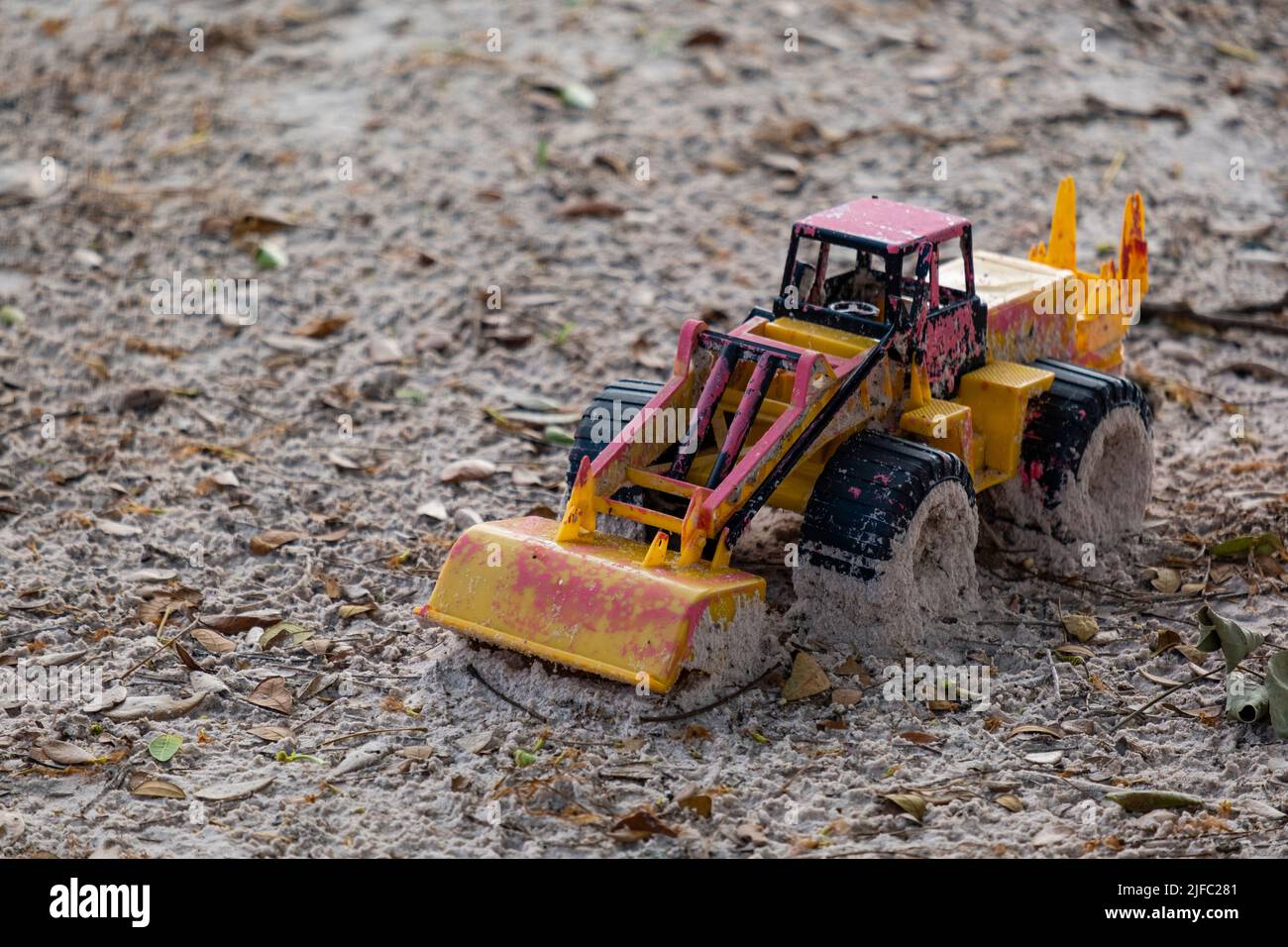 plastic toy car damaged and abandoned in sand. Stock Photo