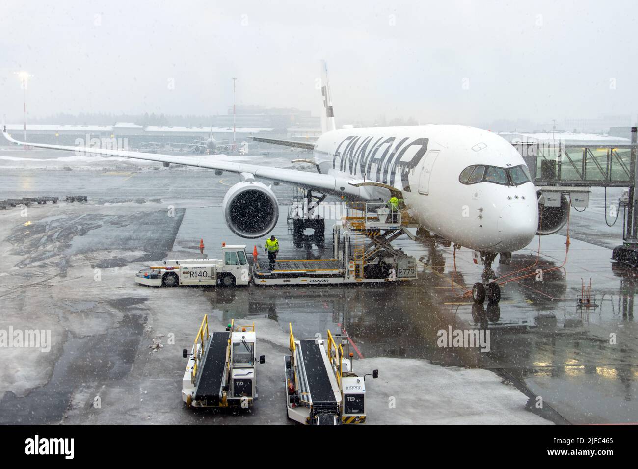 HELSINKI, FNLAND, FEB 15 2022, Snow falls on the airport, where the plane is loaded before takeoff, Helsinki Airport, Finland. Stock Photo