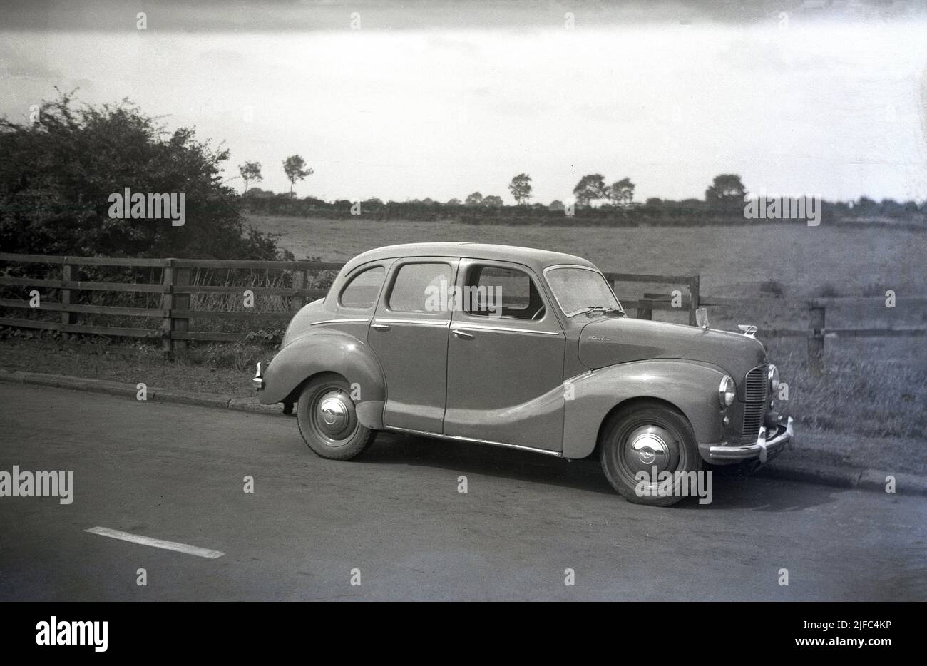 1950s, historical, side view of an Austin car of the era, an A40 Devon saloon parked on a country road, England. Produced between 1947 and 1952, the car was the first post-war saloon made by the Austin Motor Company. With a mix of old and newer technologies, the motorcar was notable for its old style, conservative appearance. Stock Photo