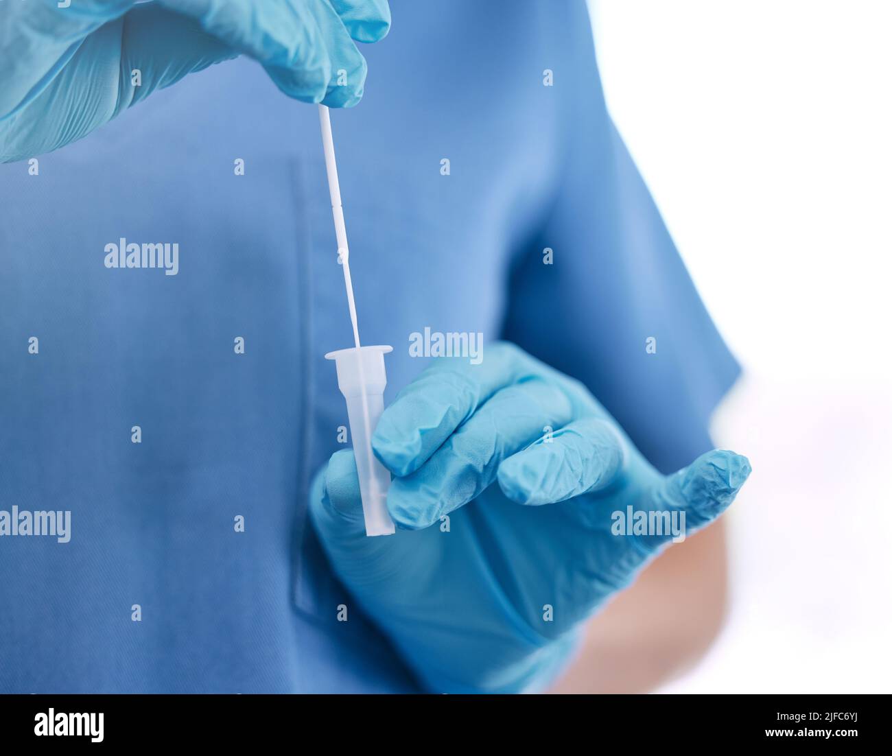 Unrecognizable doctor wearing gloves and holding a cotton swab while standing against a white studio background. Unrecognizable gp preparing to use a Stock Photo