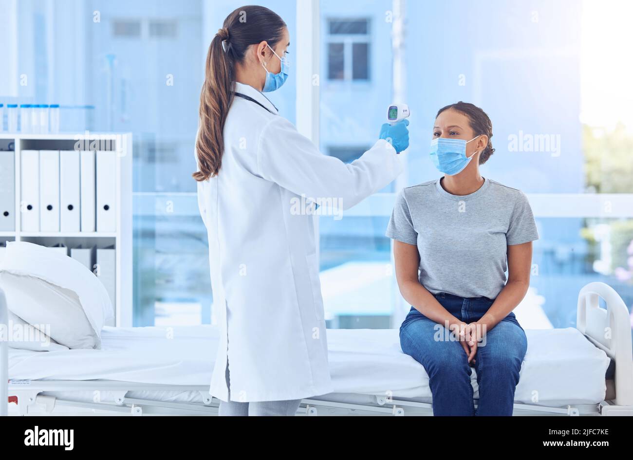 patient having her temperature checked with a thermometer. Doctor using a thermometer to scan a patients temperature. Patient in consult with doctor Stock Photo
