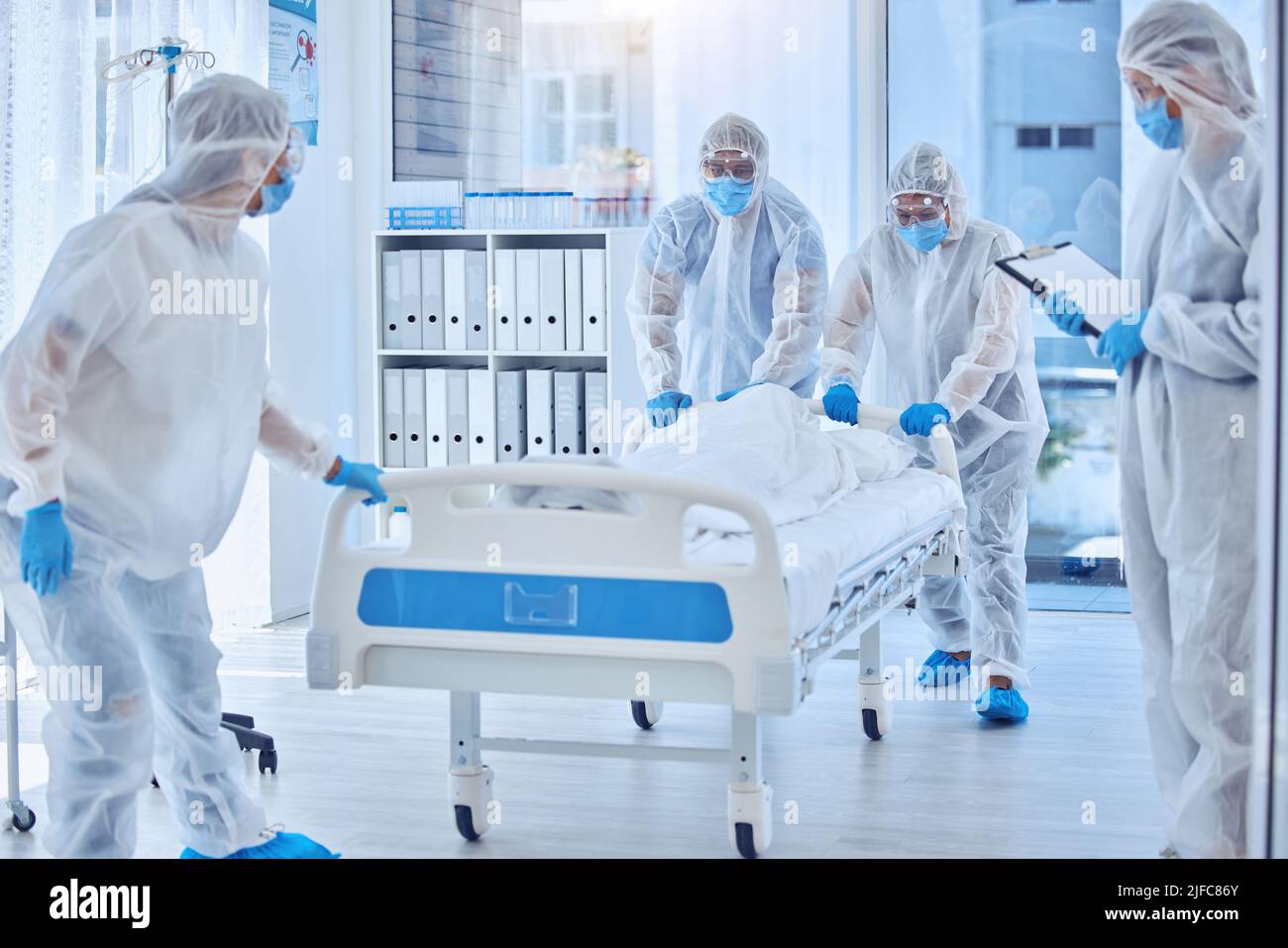 Medical science team moving hospital bed. Biohazard team in hazmat