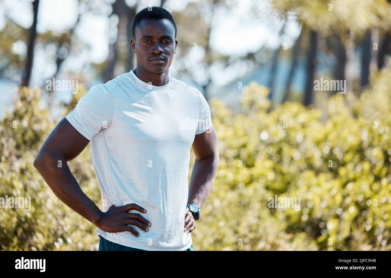 Young fit active african black male runner wearing sportswear and a watch standing with his hands on his hips looking serious and confident after a Stock Photo