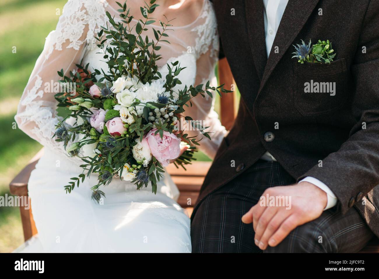 Bride and groom sitting on bench in park, close-up Stock Photo - Alamy