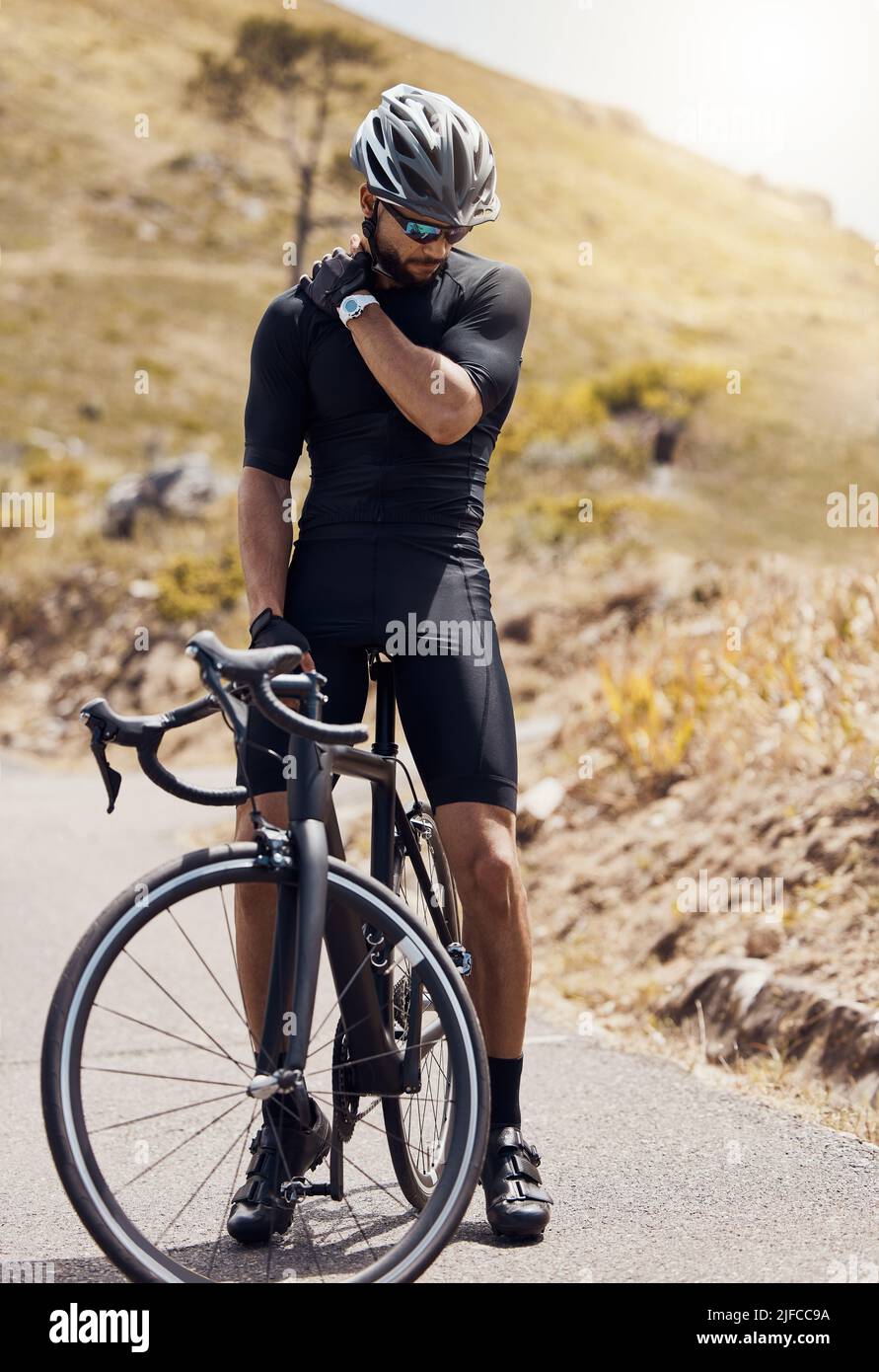 Male cyclist holding his shoulder in pain while suffering from a sports ...