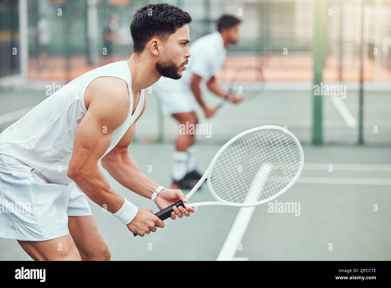 Two ethnic tennis players holding rackets and ready to play court game ...
