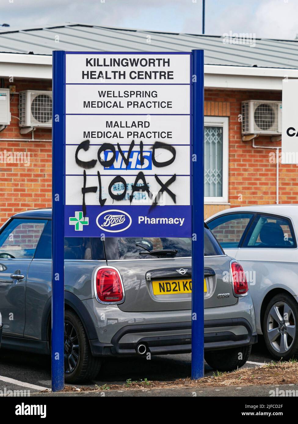 Covid hoax graffiti on a UK medical practice sign. Stock Photo